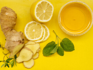 Ingredients for tea - honey, lemon, ginger on a yellow background