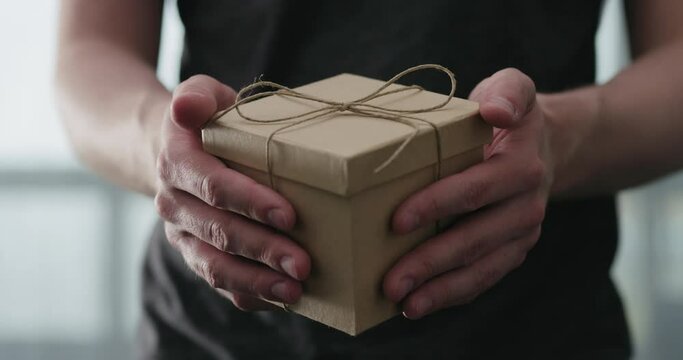 Slow motion young man shows brown craft paper gift box