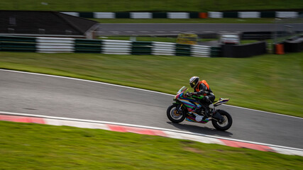 A panning shot of a multicoloured racing bike as it circuits a track