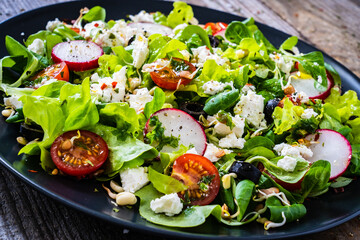 Fresh Greek salad - feta cheese, cherry tomatoes, lettuce and onion wooden table
