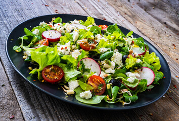 Fresh Greek salad - feta cheese, cherry tomatoes, lettuce and onion wooden table
