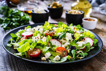 Fresh Greek salad - feta cheese, cherry tomatoes, lettuce and onion wooden table
