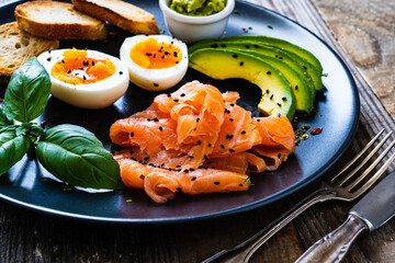 Salmon salad - smoked salmon boiled egg and vegetables on wooden background

