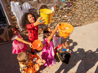 Group of children lift up buckets in the air on Halloween to get candies view from above