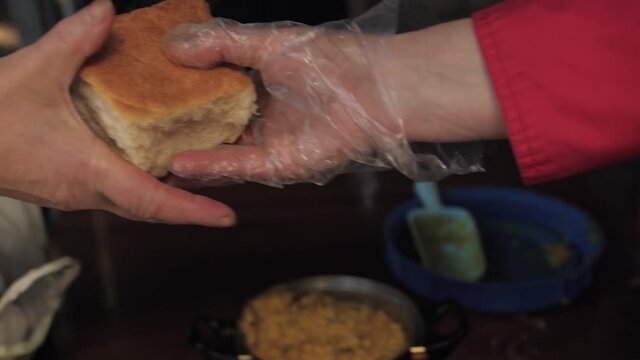 volunteer hands bread to a hungry elderly man