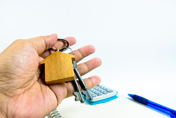 Conceptual image of debt service ratio for home loan repayment appraisal. Wooden key chain calculator notepad and pen in visibility. Focus on keychain.