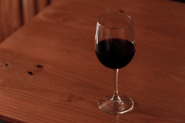 old wicker jerrycan of wine with its bottle and glass of wine on wooden table