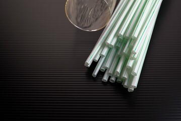 Conceptual of world issue on single use plastic against reusable steel straw.  Plastic straws in visibility on dark surface. Low key image.