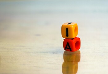 Conceptual of artificial intelligence in future. 2 colorful alphabet beads stacked on each other isolated on reflective surface. Focus on texts on beads. Others gradient blur.