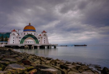 Image of Malacca straits mosque located on the man-made island in Malacca, Malaysia officially opened Nov 2006. Gloomy morning after dawn with cloudy sky in visibility. Selective focus on mosque.