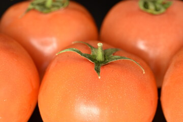 Fresh ripe, juicy, organic tomatoes, close-up, on a black background.