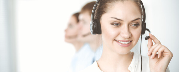 Naklejka premium Call center. Diverse customer service operators in headsets at work in office. Business concept