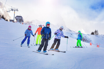 Group of children ski downhill together in colorful outfit on Alpine mountain slope