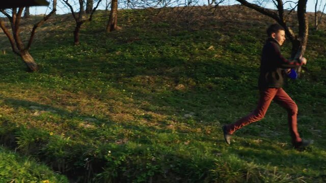 A teenage boy runs in the garden with a white purebred husky dog. Walking pets in the park. 4k video.