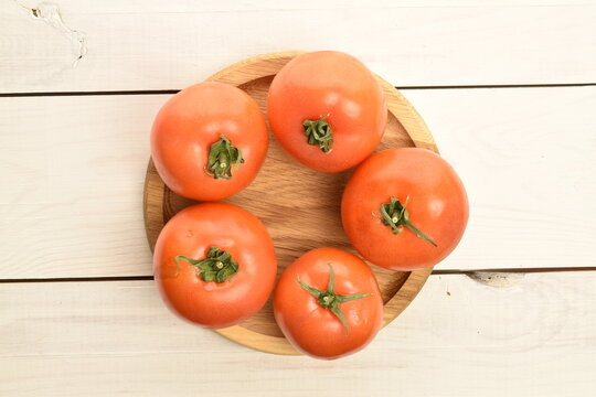 Fresh ripe, juicy, organic tomato, close-up, on a white painted, wooden table.