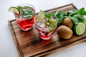Raspberry cocktail, lemonade with lime, kiwi, mint and pieces of ice on a wooden board. Close-up.