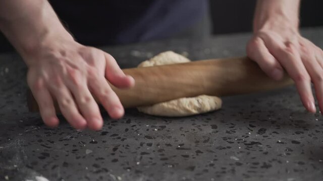 man rolling dough on concretre countertop