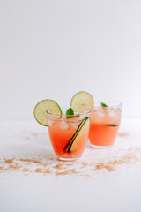 Grapefruit cocktail, lemonade with lime, mint and pieces of ice on a white table with cane sugar.