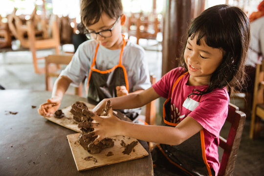 brother and sister try to make handicrafts from clay in the pottery workshop gallery