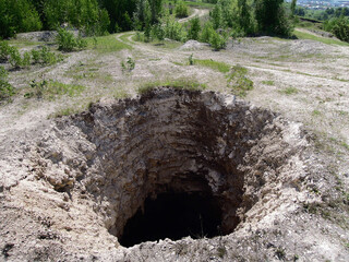 Huge karst sinkhole leading to abandoned limestone mine. Diameter of hole is about 15-18 feet,...