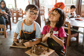 brother and sister try to make handicrafts from clay in the pottery workshop gallery