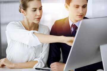 Business people discussing something while sitting in sunny office. Focus at businesswoman while talking to her male colleague