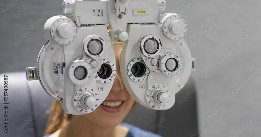 Wall mural woman checks her eye in clinic