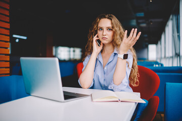 Skilled copywriter having mobile conversation while remotely working in cafe