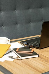 Office workplace with laptop, cup of coffee and paperwork without people.