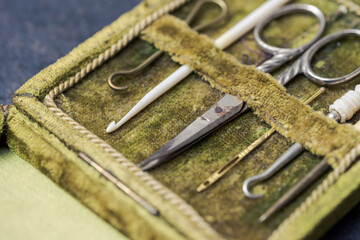 Detail of antique rare sewing kit in open green velvet box with scissor, sewing needles and crochet hooks made of metal and animal bones in very good condition