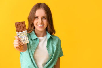 Beautiful young woman with tasty chocolate on color background