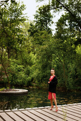 Fototapeta premium girl in the park in summer in a red dress and black jacket. Stylish urban image