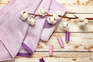 Cotton flowers, threads and soft towels on wooden background