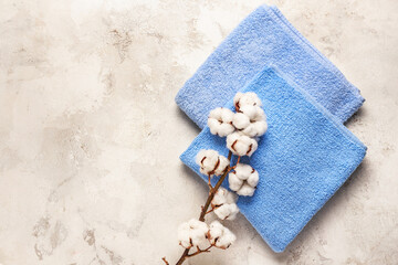 Cotton flowers and soft towels on light background