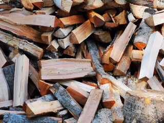 A pile of firewood near the house in the summer. Harvesting wood for heating for the winter.