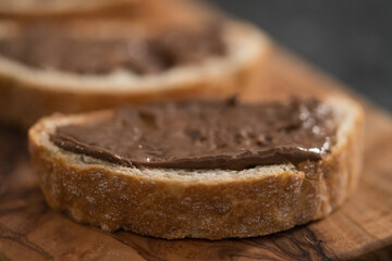 Fototapeta na wymiar Ciabatta slices with chocolate spread on olive wood board