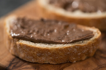 Ciabatta slices with chocolate spread on olive wood board