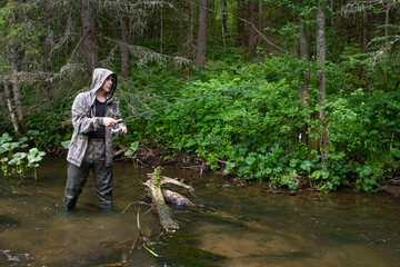 angler with a spinning rod on a forest river