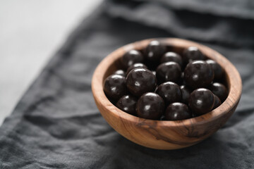 Chocolate drage with hazelnuts nuts in olive wood bowl