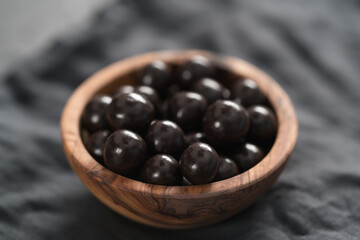 Chocolate drage with hazelnuts nuts in olive wood bowl