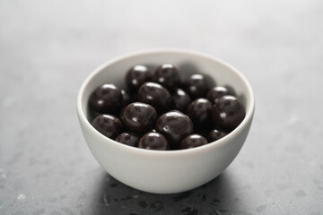Chocolate drage with hazelnuts nuts in white bowl on concrete background