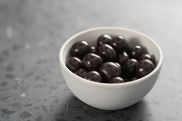 Chocolate drage with hazelnuts nuts in white bowl on concrete background