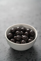 Chocolate drage with hazelnuts nuts in white bowl on concrete background