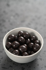 Chocolate drage with hazelnuts nuts in white bowl on concrete background