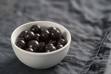 Chocolate drage with hazelnuts nuts in white bowl on linen background