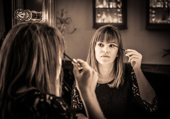 woman looking into a vintage mirror at herself and use cosmetic vanity make up accessories, makeup dressing table