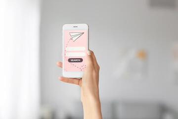 Female tourist with mobile phone booking tickets online at home