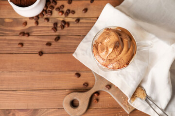 Glass cup of tasty dalgona coffee on table