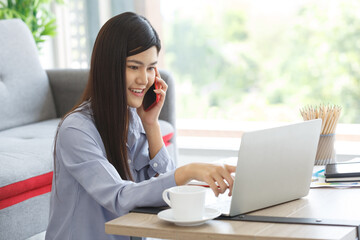 Young Cute Woman feels happy while working using Laptop and Mobile Phone on Work For Home Period. COVID-19 Lock Down.  Copy Space.