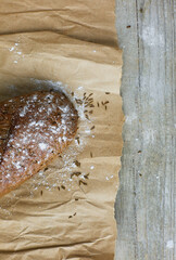 A loaf of Bread packed in paper on wooden table